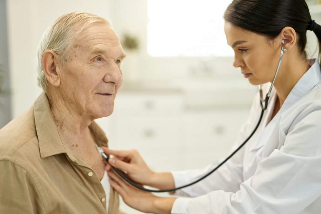 Qualified medic examining senior man lungs with stethoscope