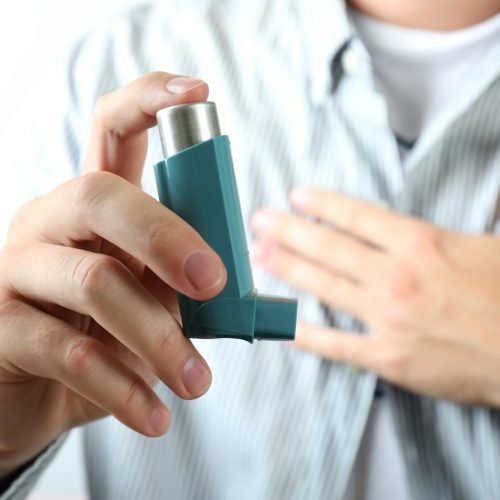Young man holds asthma inhaler during asthma attack